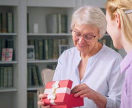 Young daughter giving a gift to an elderly mother for mother's day