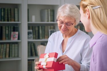 Young daughter giving a gift to an elderly mother for mother's day