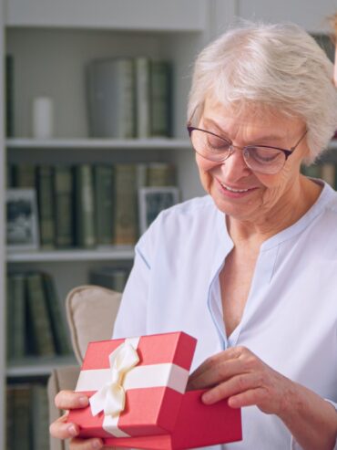 Young daughter giving a gift to an elderly mother for mother's day