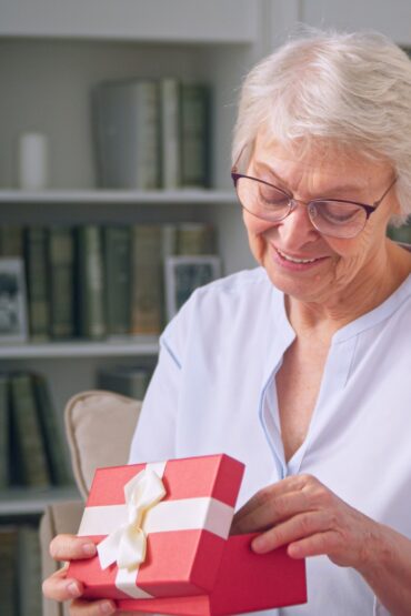 Young daughter giving a gift to an elderly mother for mother's day