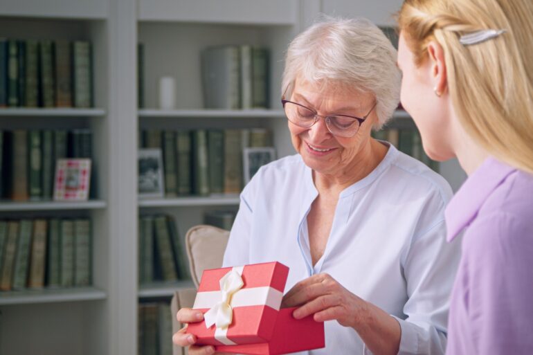 Young daughter giving a gift to an elderly mother for mother's day