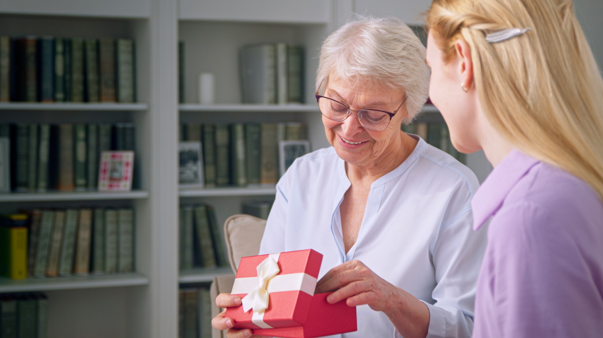 Young daughter giving a gift to an elderly mother for mother's day